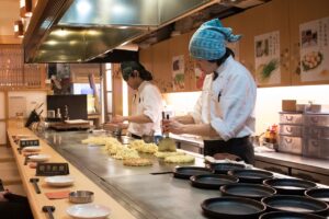 Japanische Köche bei der Zubereitung von Okonomiyaki